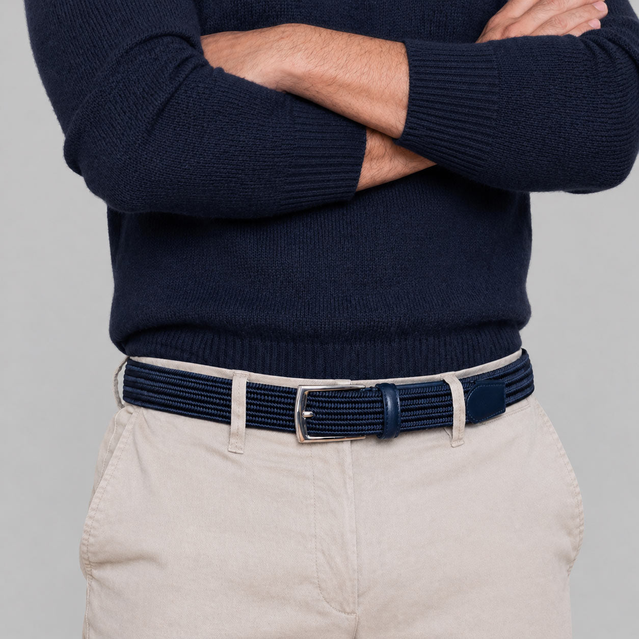 Person wearing a navy sweater and beige pants with a navy mens belt 