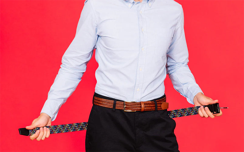 A person wearing a light blue shirt and black trousers holding a Beltology belt