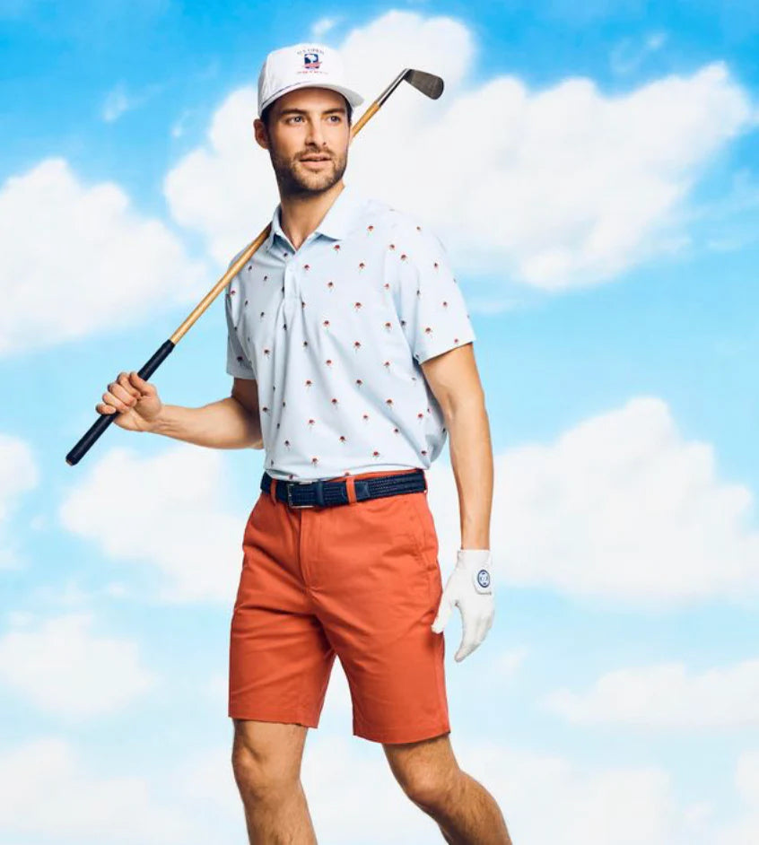 A man modeling a light blue short-sleeve polo shirt with a golf belt 