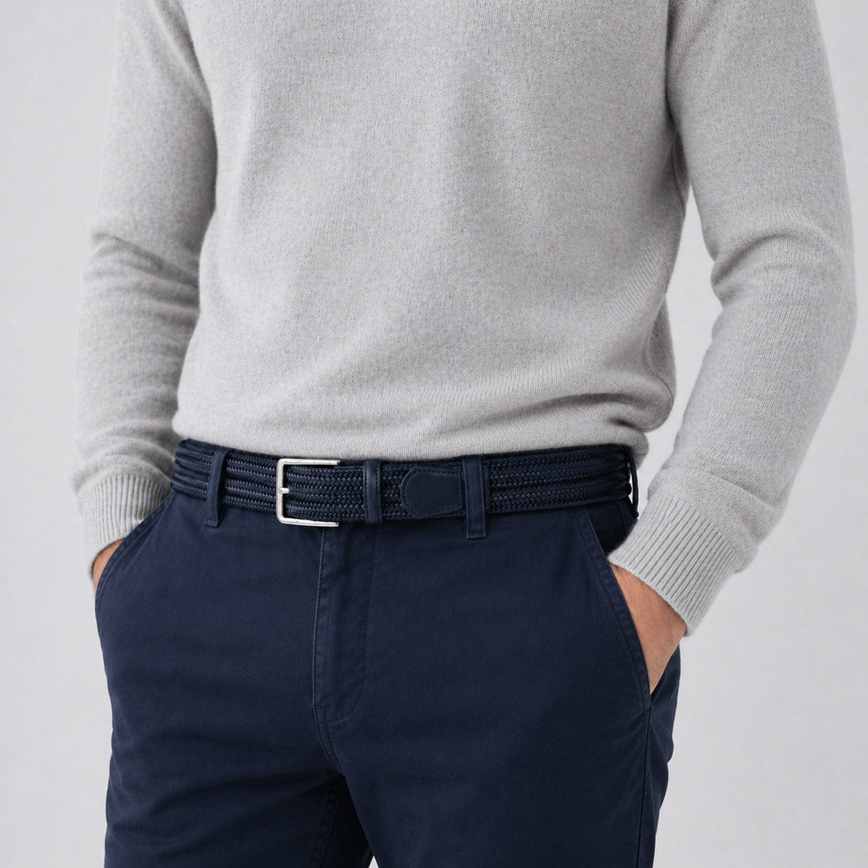 Person wearing a gray sweater and navy pants with a mens belt