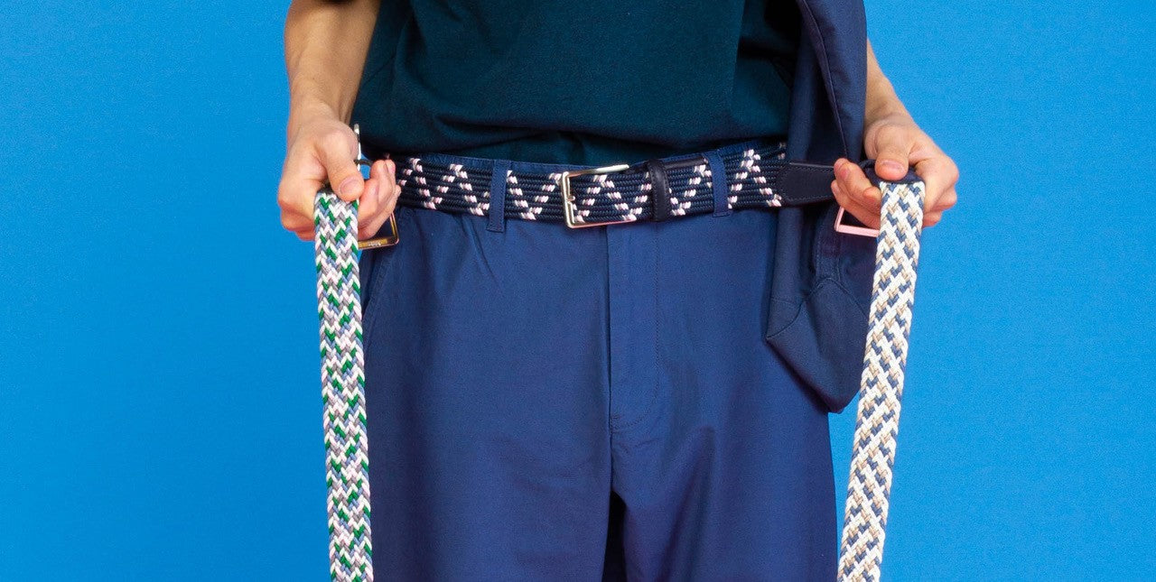 Model holding a Beltology mens belt with a blue background
