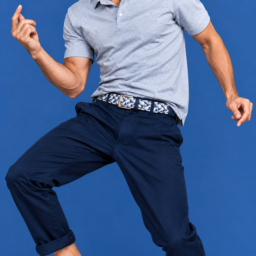 A man wearing a light gray short-sleeve polo shirt, navy blue pants, and a patterned men's belt